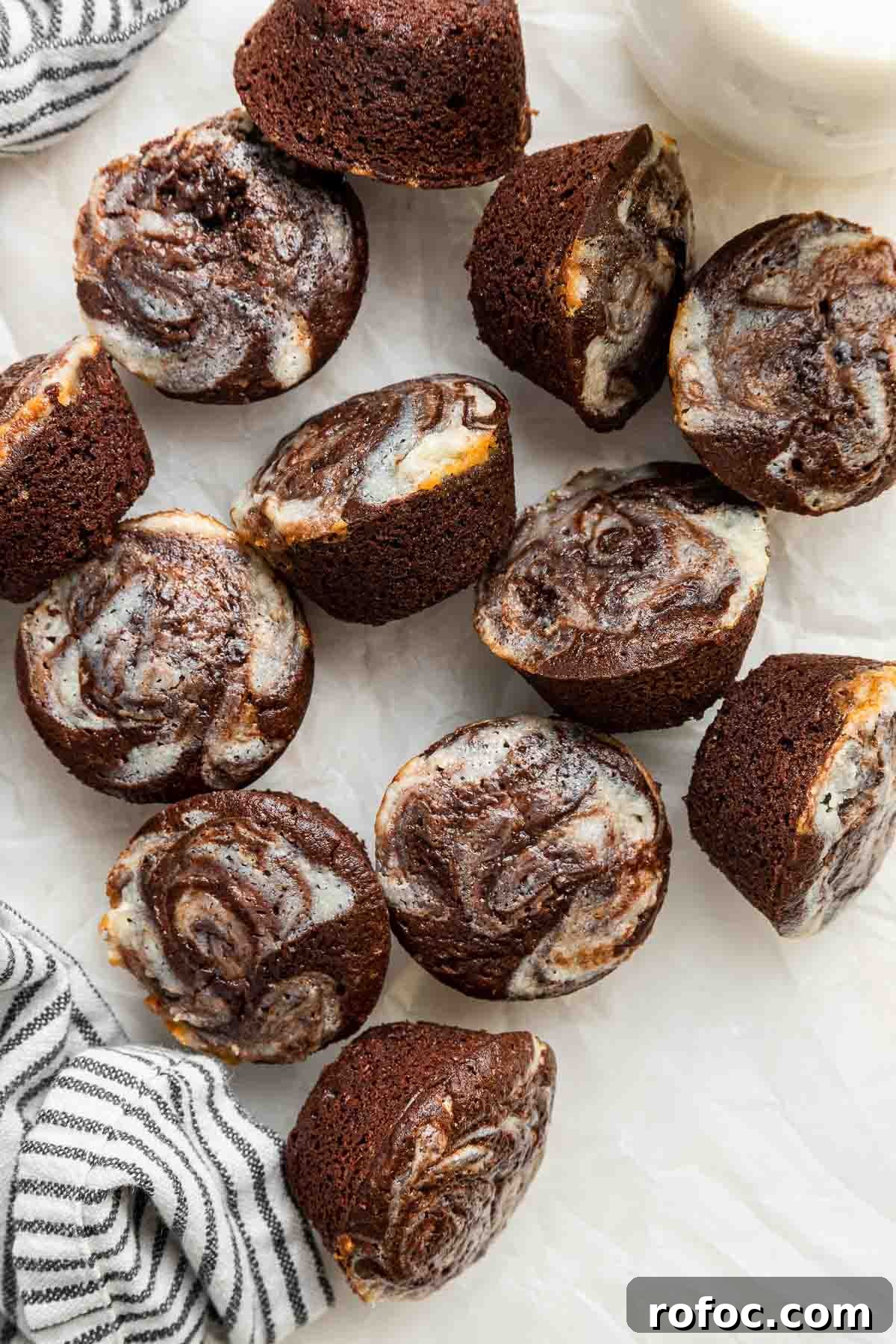 Cheesecake Brownie Bites: Mini Dessert Recipe for Parties 14 Overhead shot of mini cheesecake brownie bites on white table with blue napkin.