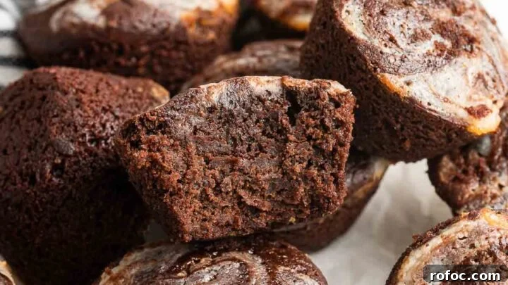 Cheesecake brownie bites piled up with one cut in half to show fudginess inside.