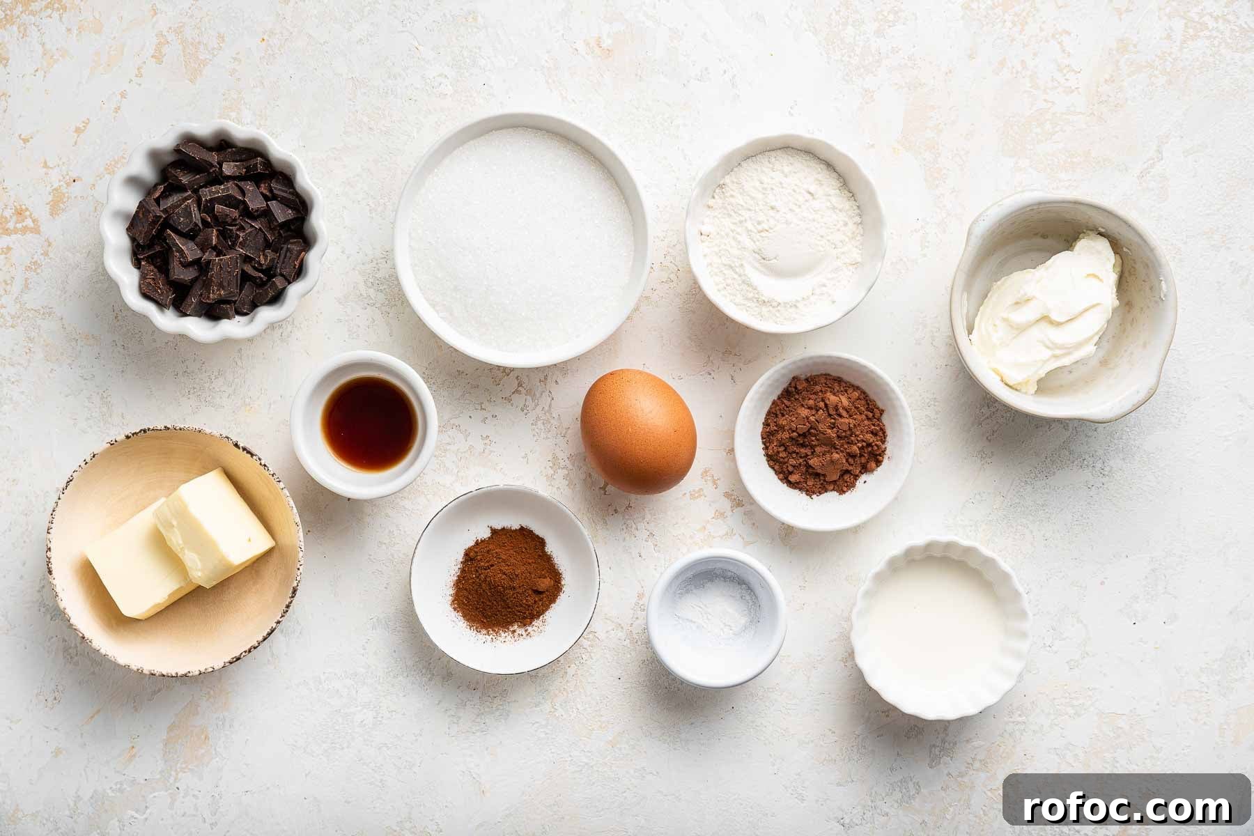 Cheesecake Brownie Bites: Mini Dessert Recipe for Parties 4 Small white bowls of chopped chocolate, butter, sugar, egg, and cocoa powder.