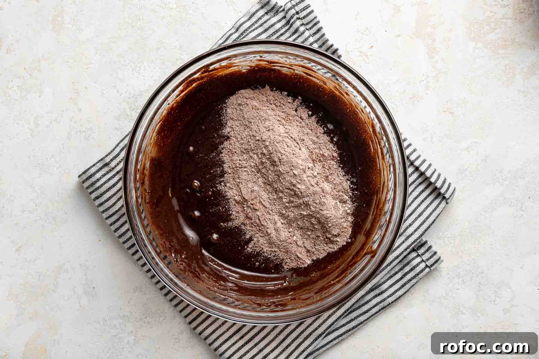 Cheesecake Brownie Bites: Mini Dessert Recipe for Parties 8 Adding dry ingredients to wet brownie batter in mixing bowl.