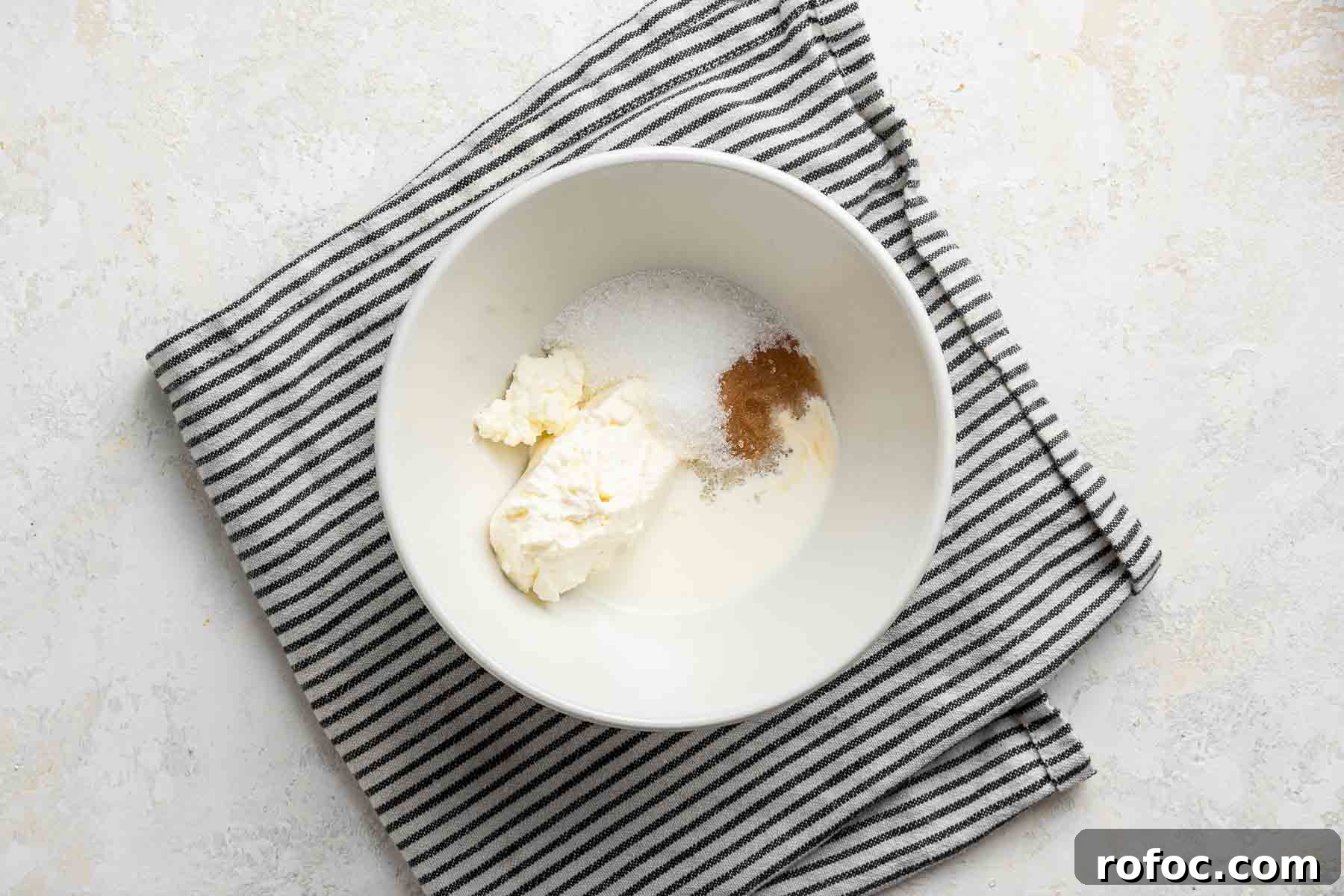 Cheesecake Brownie Bites: Mini Dessert Recipe for Parties 9 Cream cheese, sugar, vanilla and heavy cream in a white bowl.