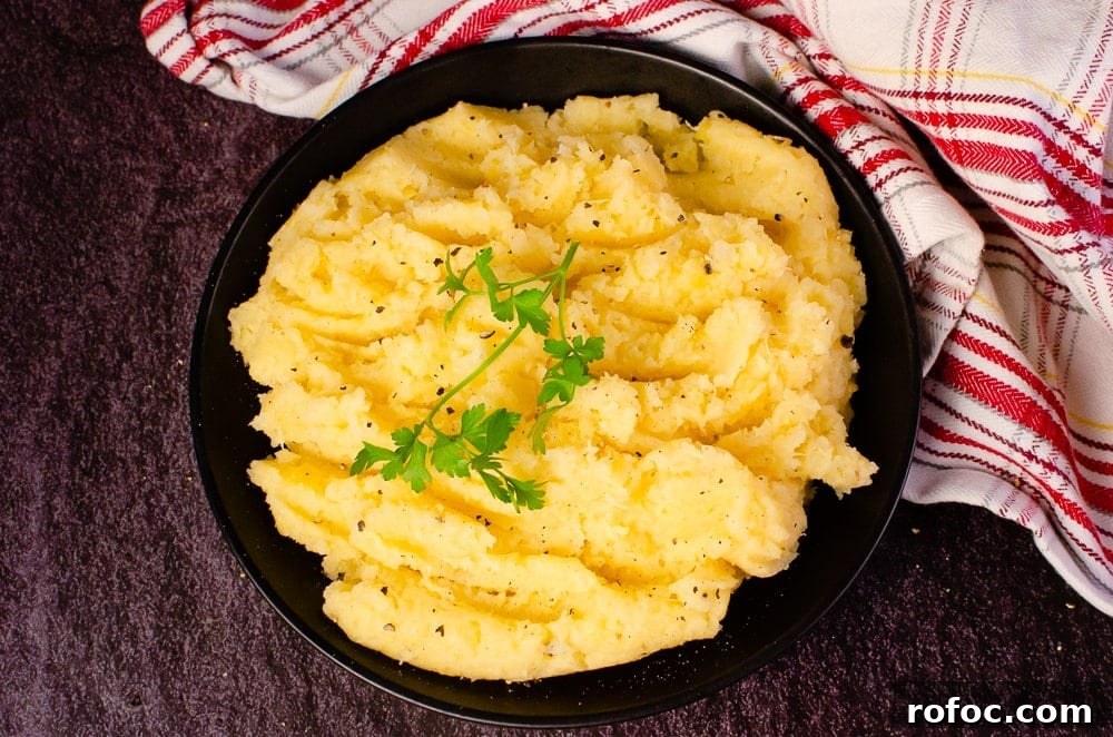 Creamy Buttered Swede served in a black bowl with parsley on top next to a white and red towel