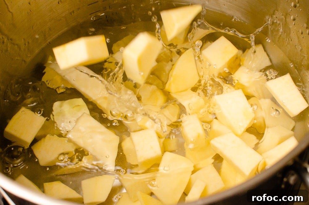Placing the cubed swede into water in a silver pot to cook