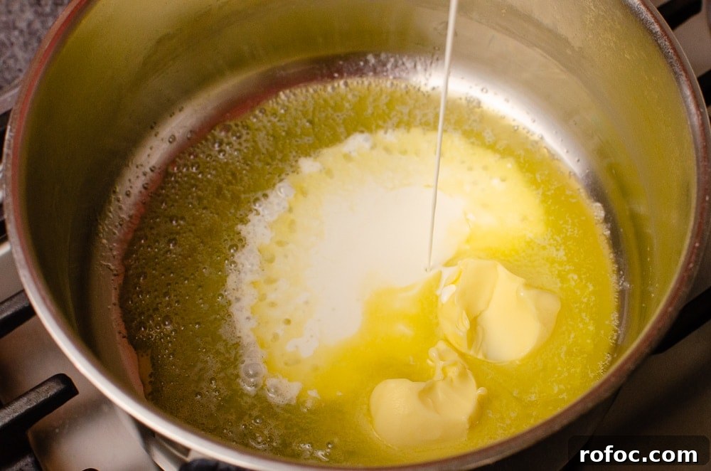 Butter and cream being poured into a silver cooking pot