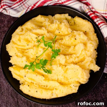 Creamy Buttered Swede served in a black bowl with parsley on top next to a white and red towel