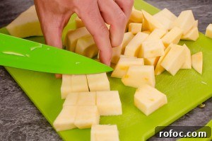 Chopping swede with a green knife into cubes on a green chopping board
