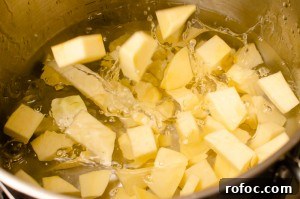 Placing the cubed swede into water in a silver pot to cook