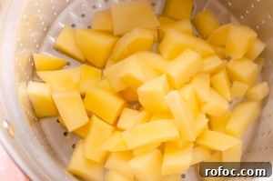 Cooked swede being drained into a silver drainer