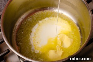 Butter and cream being poured into a silver cooking pot