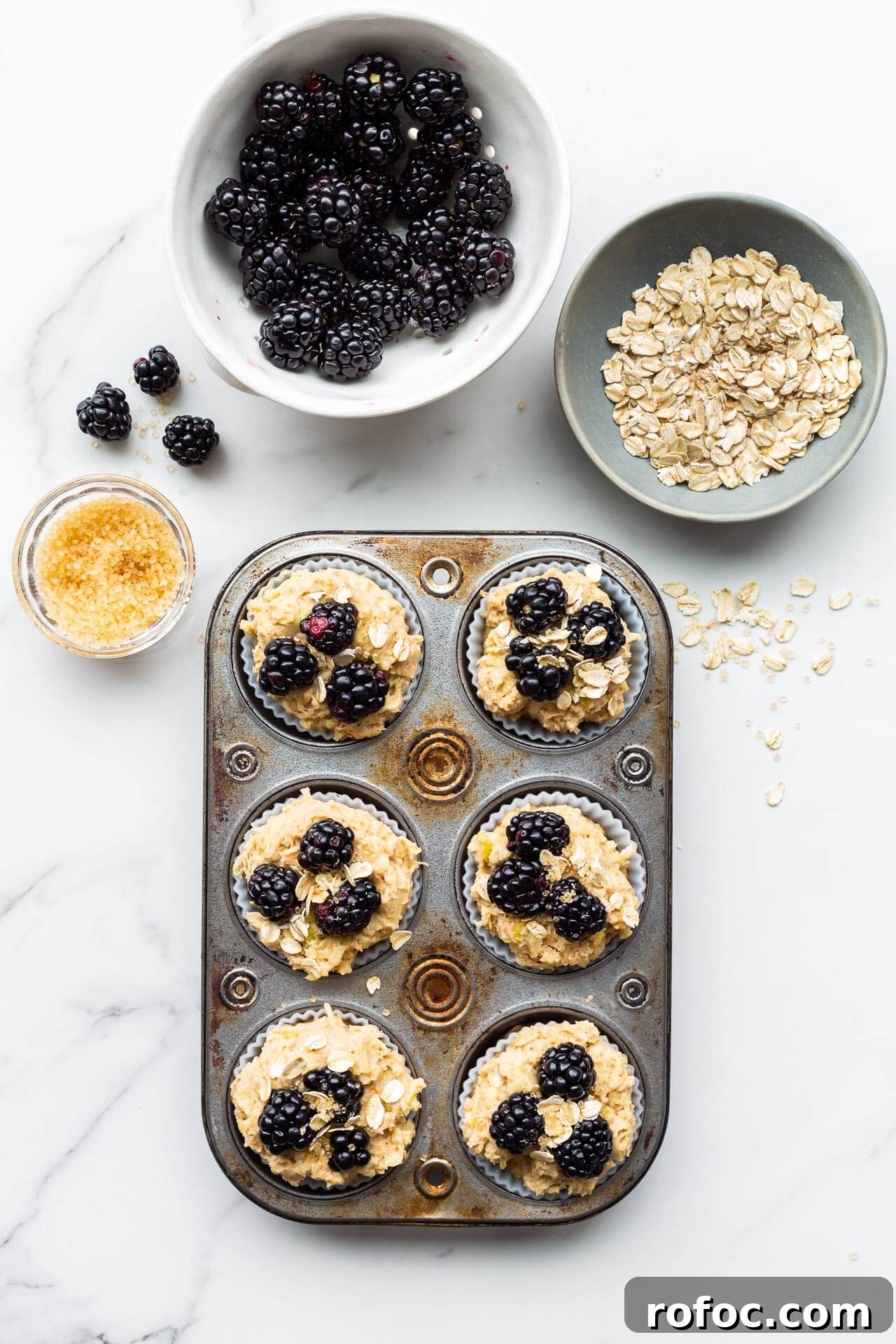 Hearty Apple and Blackberry Muffins Recipe for Fall Baking 4 Finishing apple blackberry muffins placing blackberries, oats, and turbinado sugar on top before baking