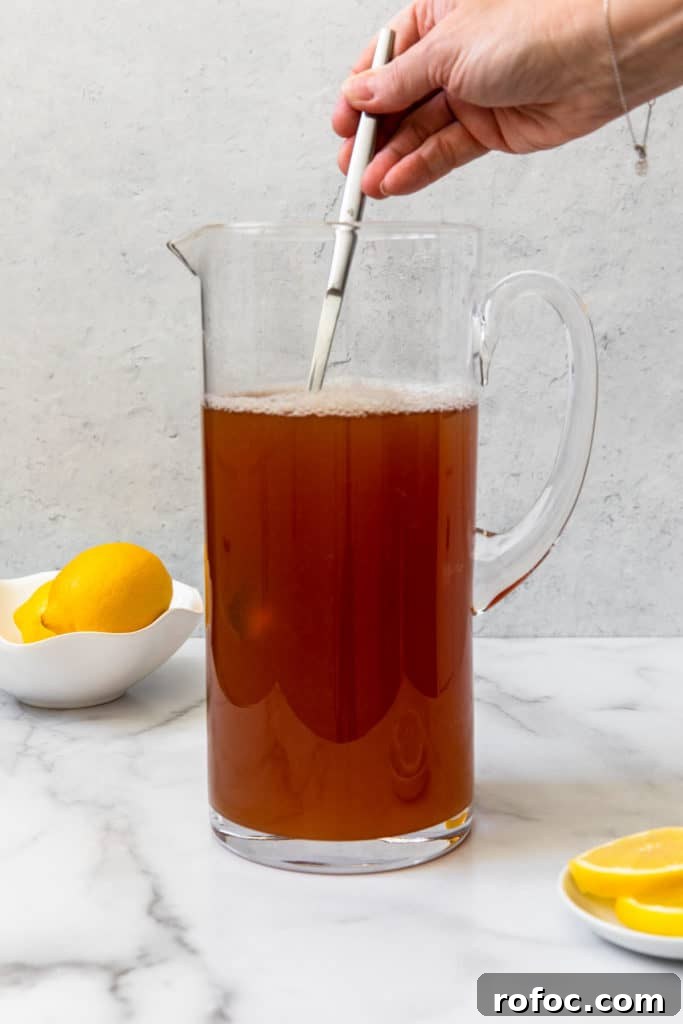 Classic Arnold Palmer Recipe + 3 Refreshing Spiked Variations 12 mixing brewed tea and lemonade in a glass pitcher