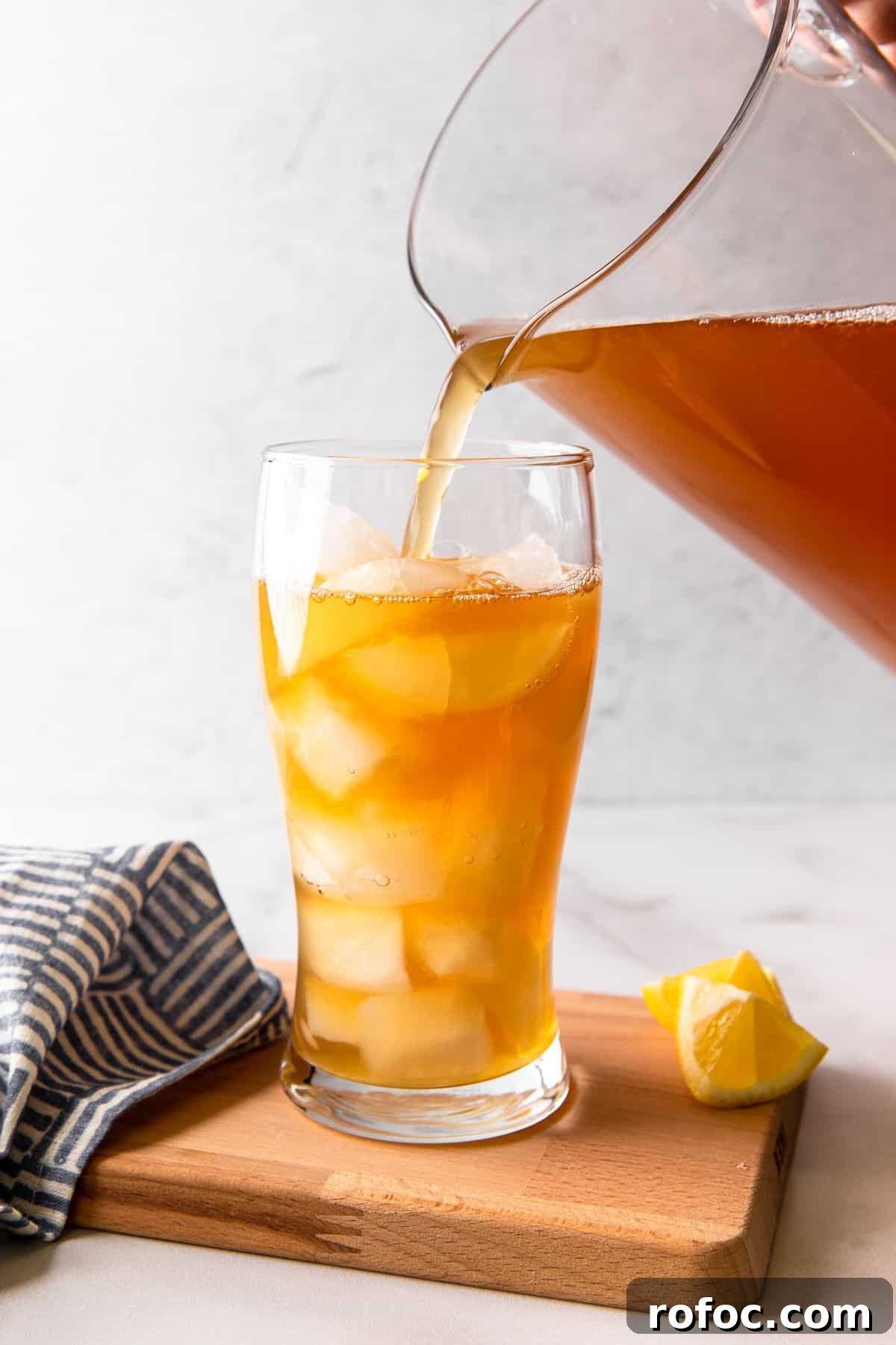 Classic Arnold Palmer Recipe + 3 Refreshing Spiked Variations 13 pouring iced tea lemonade mixture into a glass filled with ice
