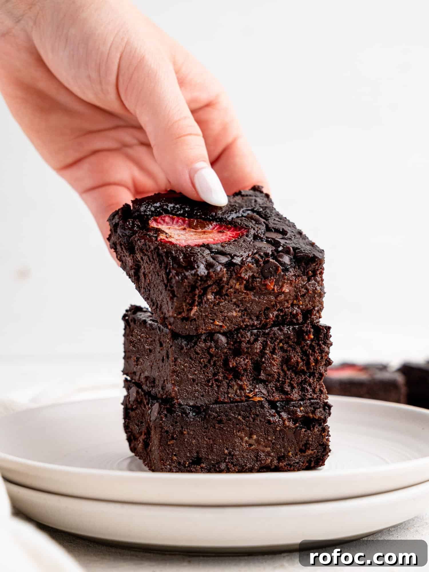 One‑Bowl Strawberry Brownies — Moist, Guilt‑Free Recipe 12 Three brownie with strawberries stacked on top of each othr on a white plate.