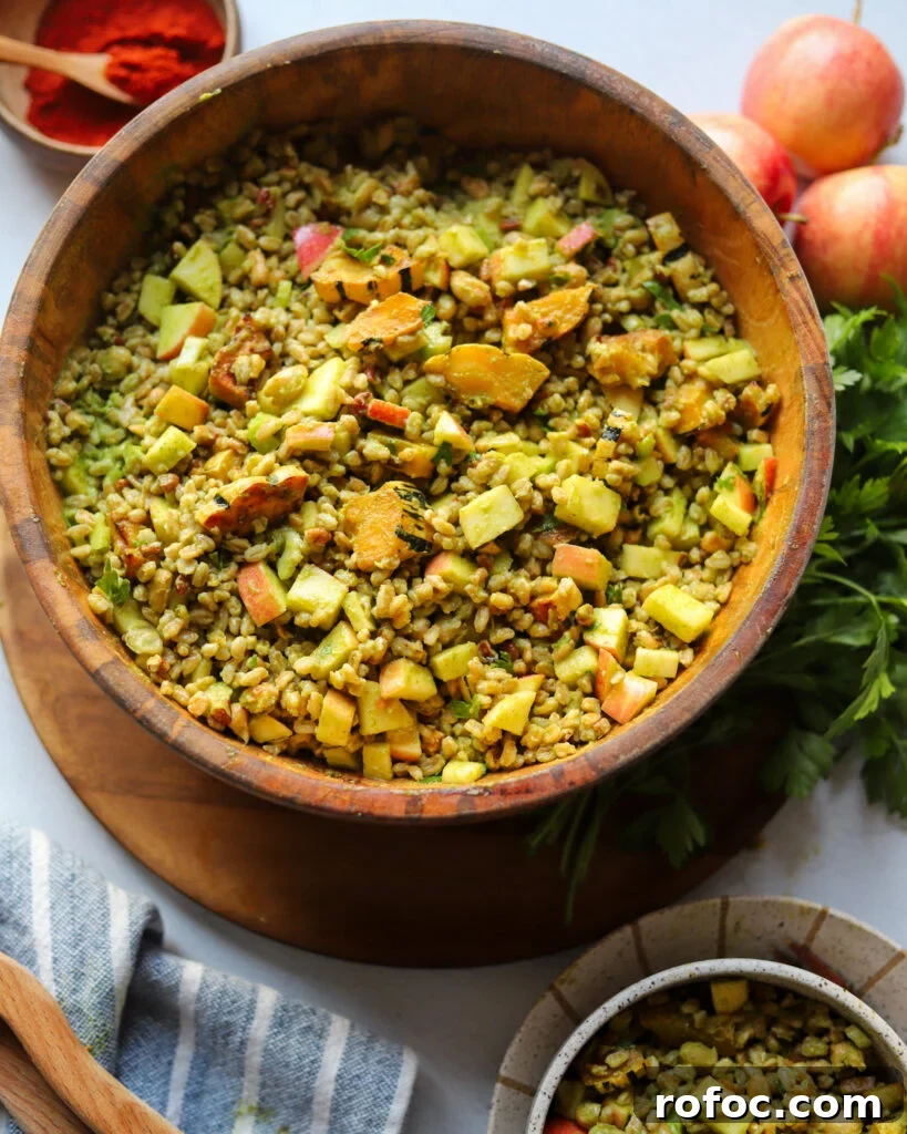 Farro Salad with Apples and Roasted Delicata Squash 2 overhead view of a wooden serving bowl with a grain salad made with farro, apple, roasted delicata squash, pecans, and more all tossed in a parsley dijon vinaigrette next to apples and fresh parsley.