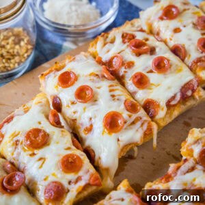 French Bread Pizza Recipe: Crispy Garlic & Cheesy Toppings 2 French bread pizza cut into slices on a wooden cutting board.
