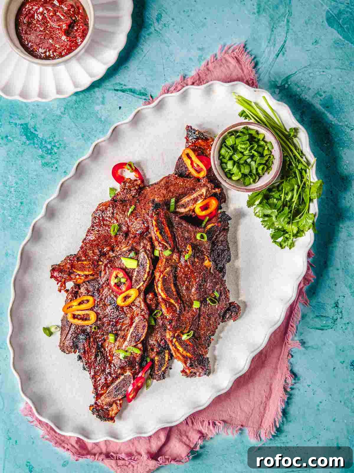 How to Cook Flanken-Style Beef Short Ribs: Recipe & Tips 2 Beef short ribs with bbq sauce on a white plate.