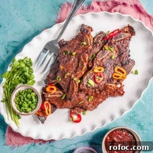 How to Cook Flanken-Style Beef Short Ribs: Recipe & Tips 12 Flanken beef short ribs on a platter with green onion and sauce.