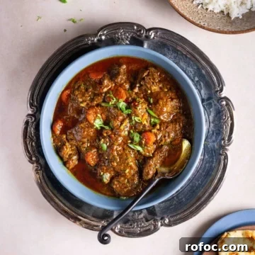 A bowl of beef masala in a tray on a flat surface.