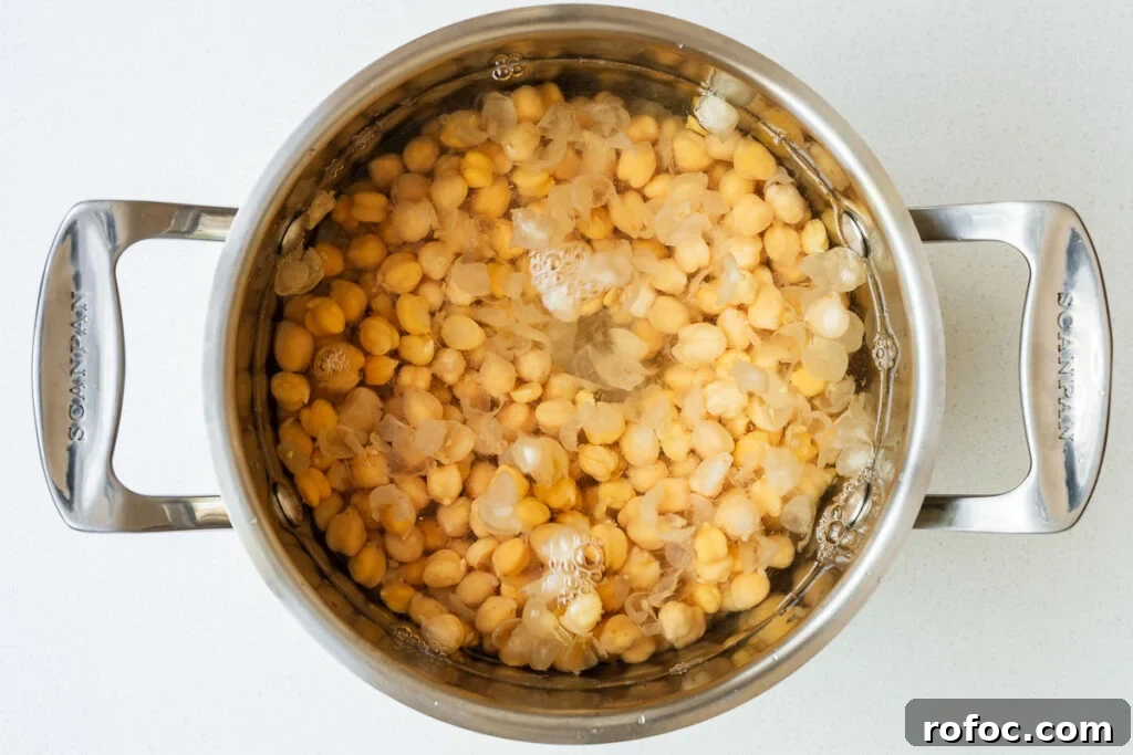 Spicy Harissa Hummus Recipe: Creamy Homemade Dip in Minutes 6 Chickpeas in a pot with water and chickpea skins floating to the top.