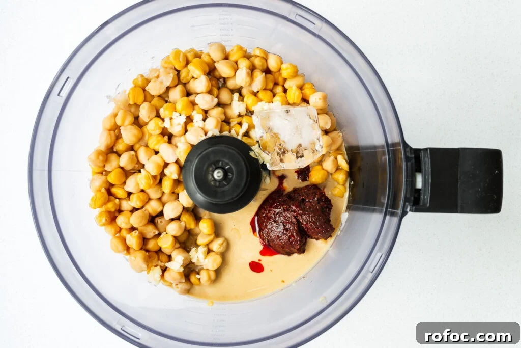 Spicy Harissa Hummus Recipe: Creamy Homemade Dip in Minutes 8 Spicy hummus ingredients in a food processor bowl viewed from above.