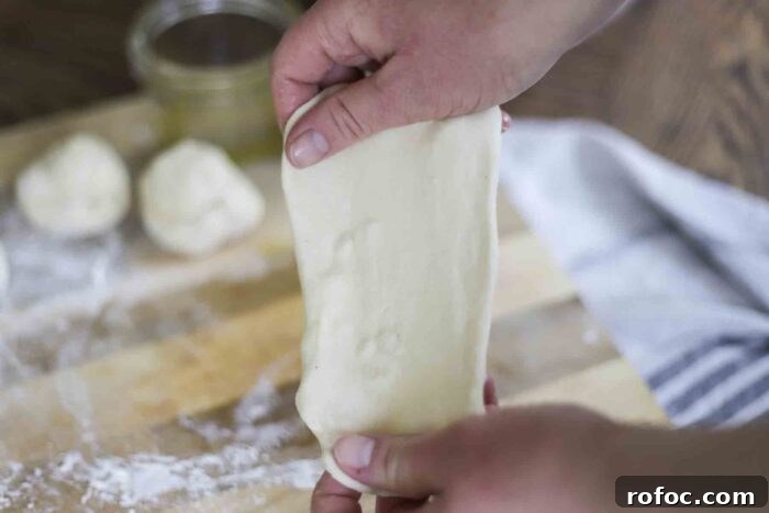 Sourdough Flatbread Recipe Using Active Starter or Discard (No Yeast) 11 hands stretching out sourdough flatbread dough with a cutting board and dough balls in the background