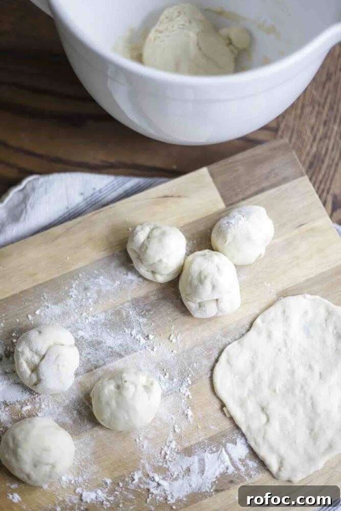 Sourdough Flatbread Recipe Using Active Starter or Discard (No Yeast) 10 six balls of dough on a lightly floured cutting board with a white bowl in the background