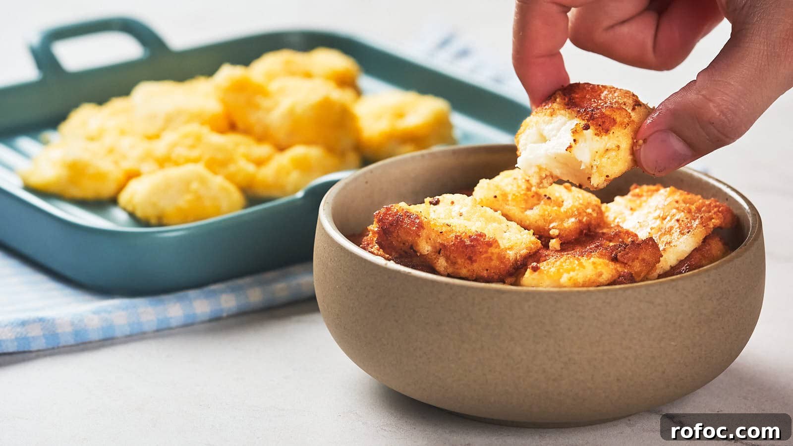 15 Low-Carb Recipes That Taste Like You Spent Hours 13 A hand picks up a piece of fried cheese curd from a bowl.