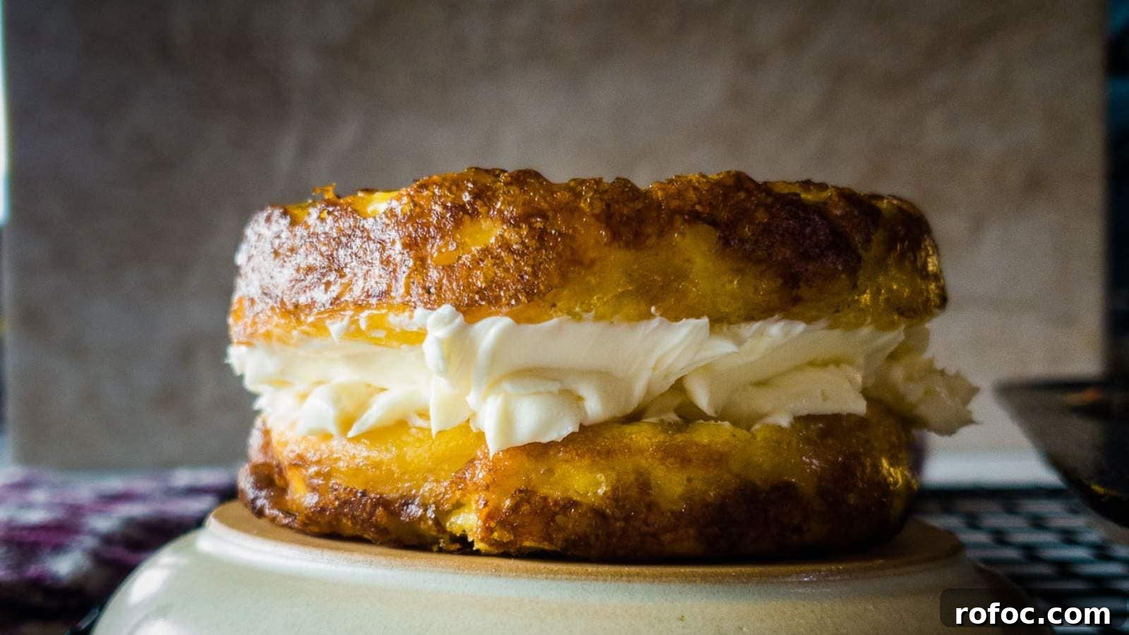 15 Low-Carb Recipes That Taste Like You Spent Hours 15 Close-up of a round, golden-brown pastry with a layer of cream frosting in the center, placed on a light-colored plate.