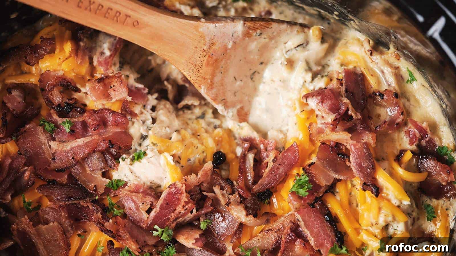 15 Low-Carb Recipes That Taste Like You Spent Hours 4 A close-up of slow cooker crack chicken being stirred with a wooden spoon.