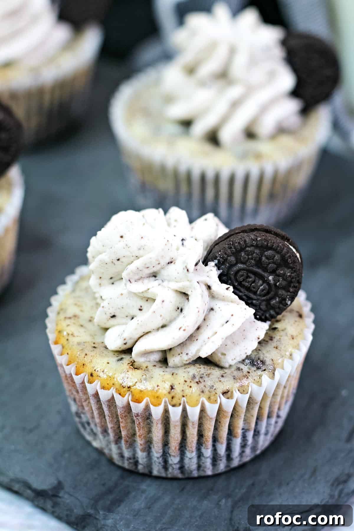 Mini Oreo Cheesecakes: Bite-Sized Dessert Recipe for Parties 2 a mini Oreo cheesecake topped with Oreo whipped cream and a mini Oreo inside a cupcake wrapper.