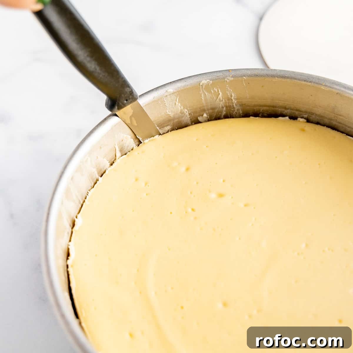 Decadent Cherry Cheesecake Recipe with a Buttery Crust 12 A knife running around the edge of the cheesecake in a cake pan.