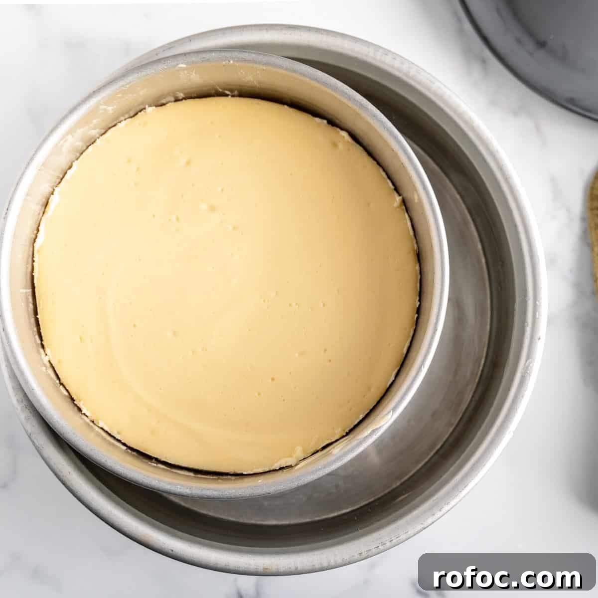 Decadent Cherry Cheesecake Recipe with a Buttery Crust 13 Dipping the cheesecake in a larger cake pan full of water.