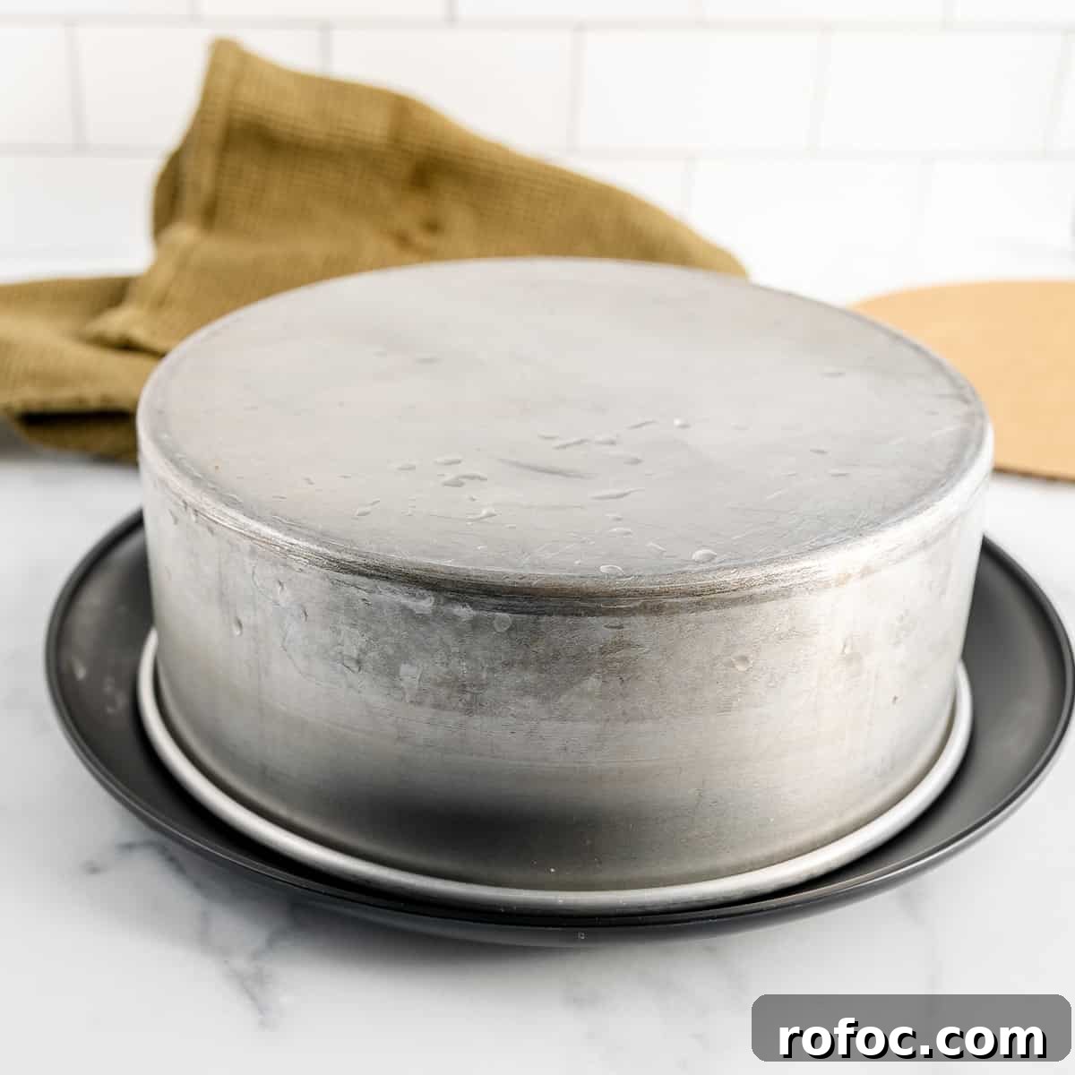 Decadent Cherry Cheesecake Recipe with a Buttery Crust 14 A cake pan turned upside down on a black plate. A green napkin in the background.