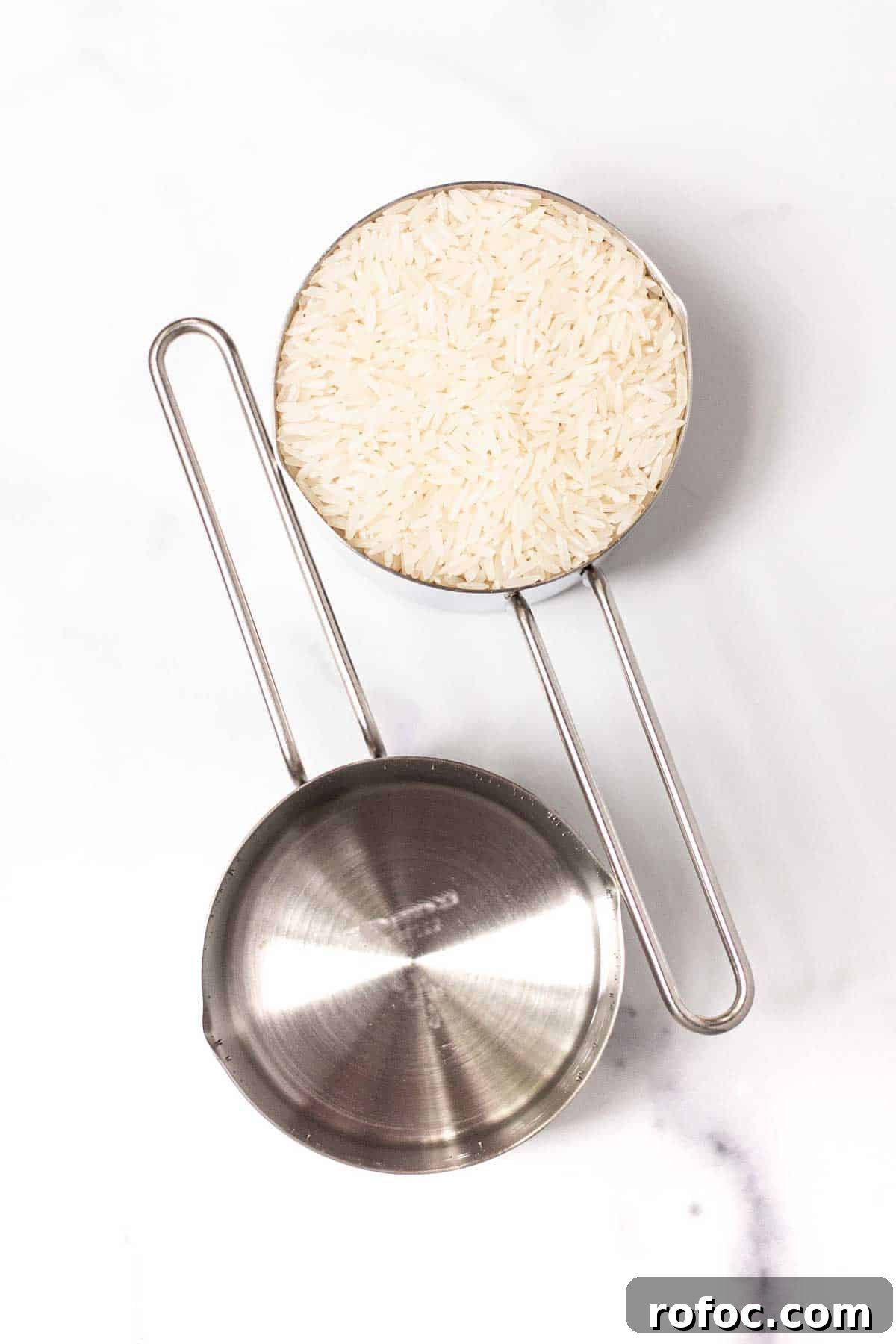 Perfect Jasmine Rice in the Instant Pot: Fluffy & Quick 3 One one-cup measuring cup filled with Jasmine rice and one one-cup measuring cup filled with water.