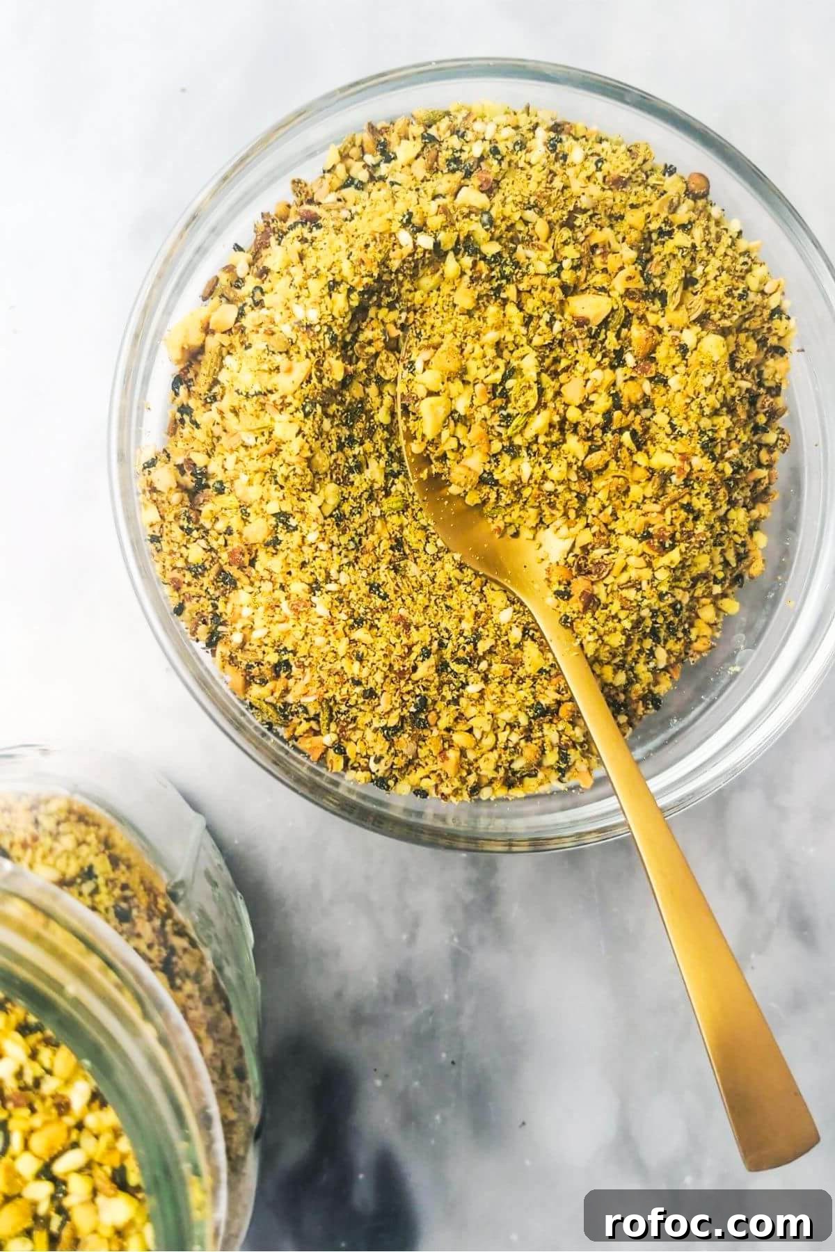 Spiced Dukkah Recipe: Crunchy Egyptian Nut & Spice Mix 2 Dukkah in a small glass bowl with a jar on the side.