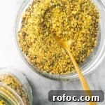 Dukkah in a small glass bowl with a jar on the side.