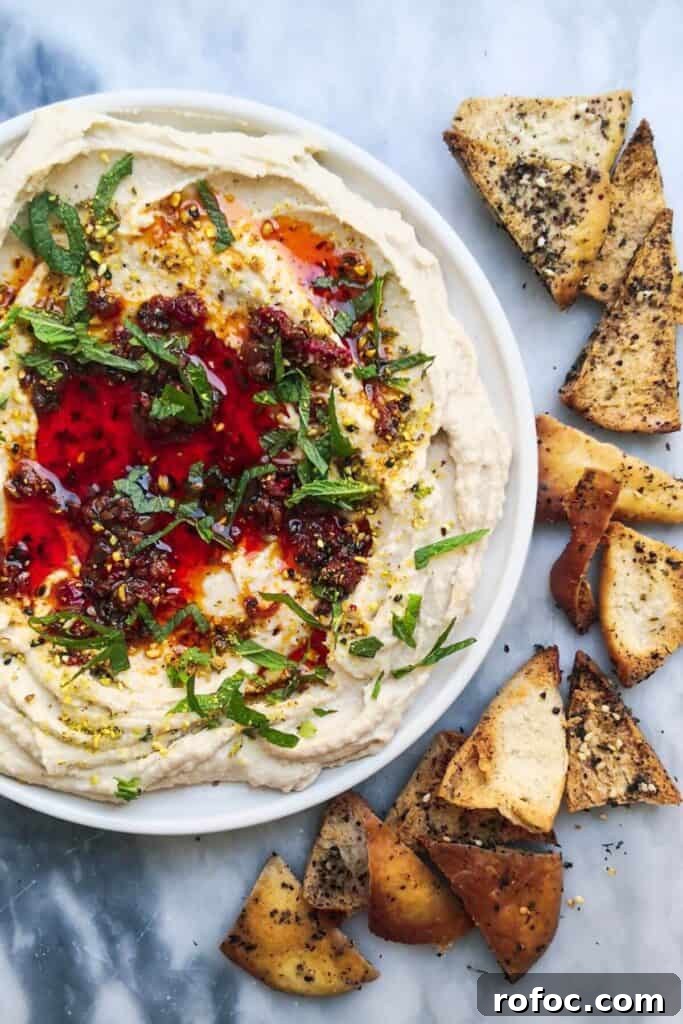 Spiced Dukkah Recipe: Crunchy Egyptian Nut & Spice Mix 10 A small white plate of chilli oil topped super smooth hummus, with pita chips on the side.
