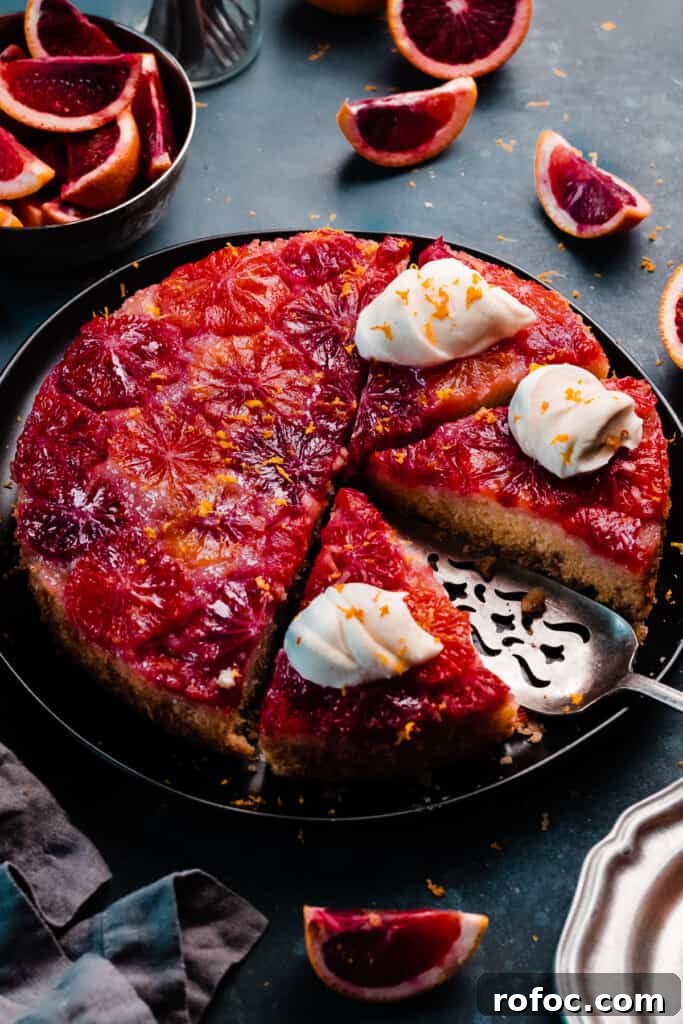 Blood Orange Upside-Down Cake Recipe & Citrus Glaze Tips 12 The sliced cake on a plate, with dollops of whipped cream on top.
