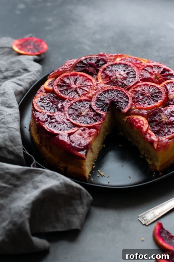 Blood Orange Upside-Down Cake Recipe & Citrus Glaze Tips 10 Blood orange upside down cake on a black plate, with one slice missing.