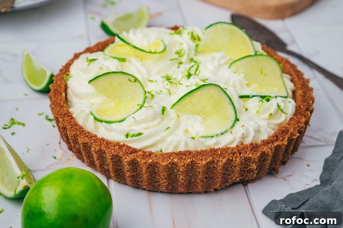 19 Fall Cookout Recipes for Sunday Dinner and Game Day 13 A key lime pie with a graham cracker crust, topped with whipped cream and lime slices, sits on a marble surface with lime wedges nearby.