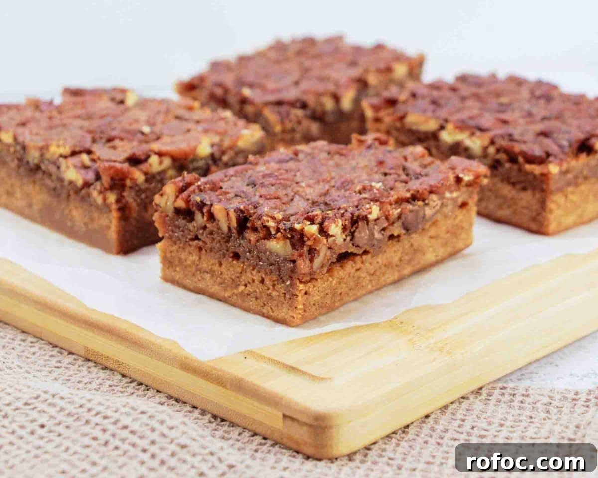 Derby Pie Brownies: Classic Kentucky Derby Dessert Recipe 2 Sideview of Derby pie brownies with chocolate chips and pecans on parchment paper - Kentucky Derby desserts - Hostess At Heart