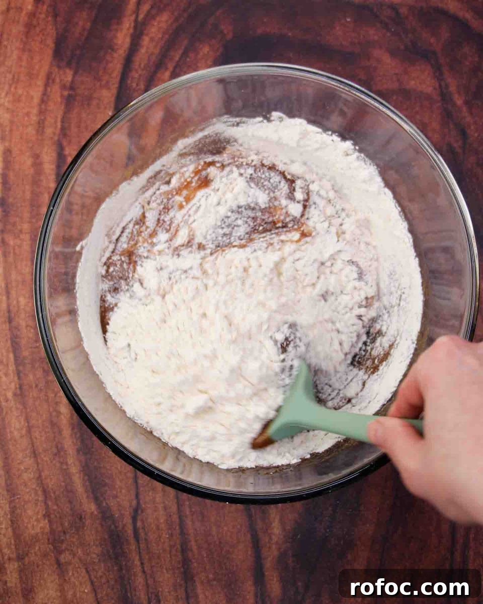 Derby Pie Brownies: Classic Kentucky Derby Dessert Recipe 5 Flour being mixed into a mixing bowl filled with the wet chocolate pecan brownie batter ingredients. Hostess At Heart
