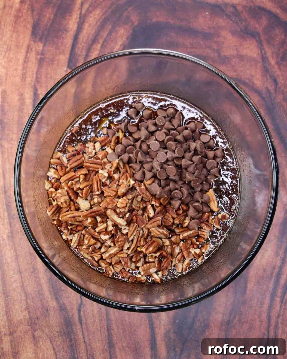 Derby Pie Brownies: Classic Kentucky Derby Dessert Recipe 9 Chopped pecans and chocolate chips added to a mixing bowl filled with pecan pie ingredients; brown sugar, corn syrup, butter, eggs and bourbon - Hostess At Heart