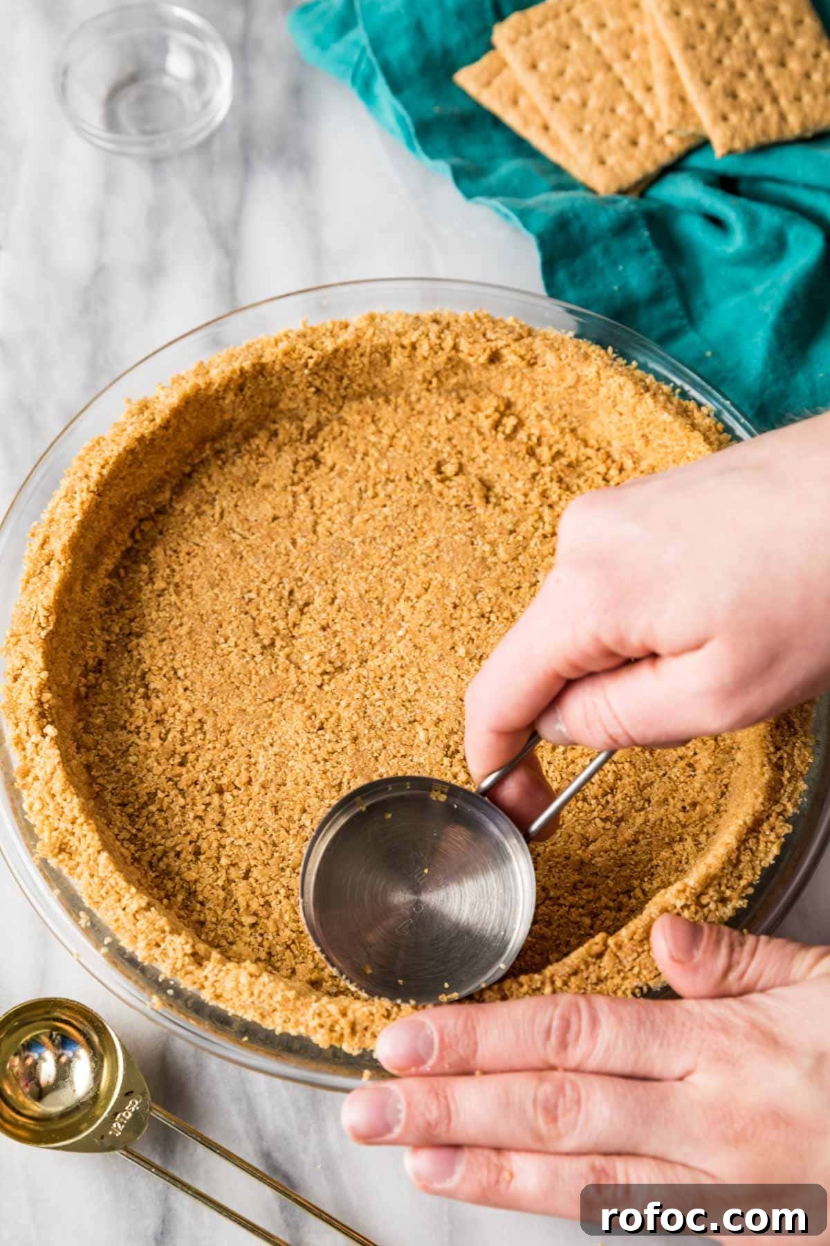 Graham Cracker Crust Recipe: Simple Steps for Perfect Pie Crust 8 Using a metal measuring cup to tamp graham cracker crumbs into a glass pie plate.