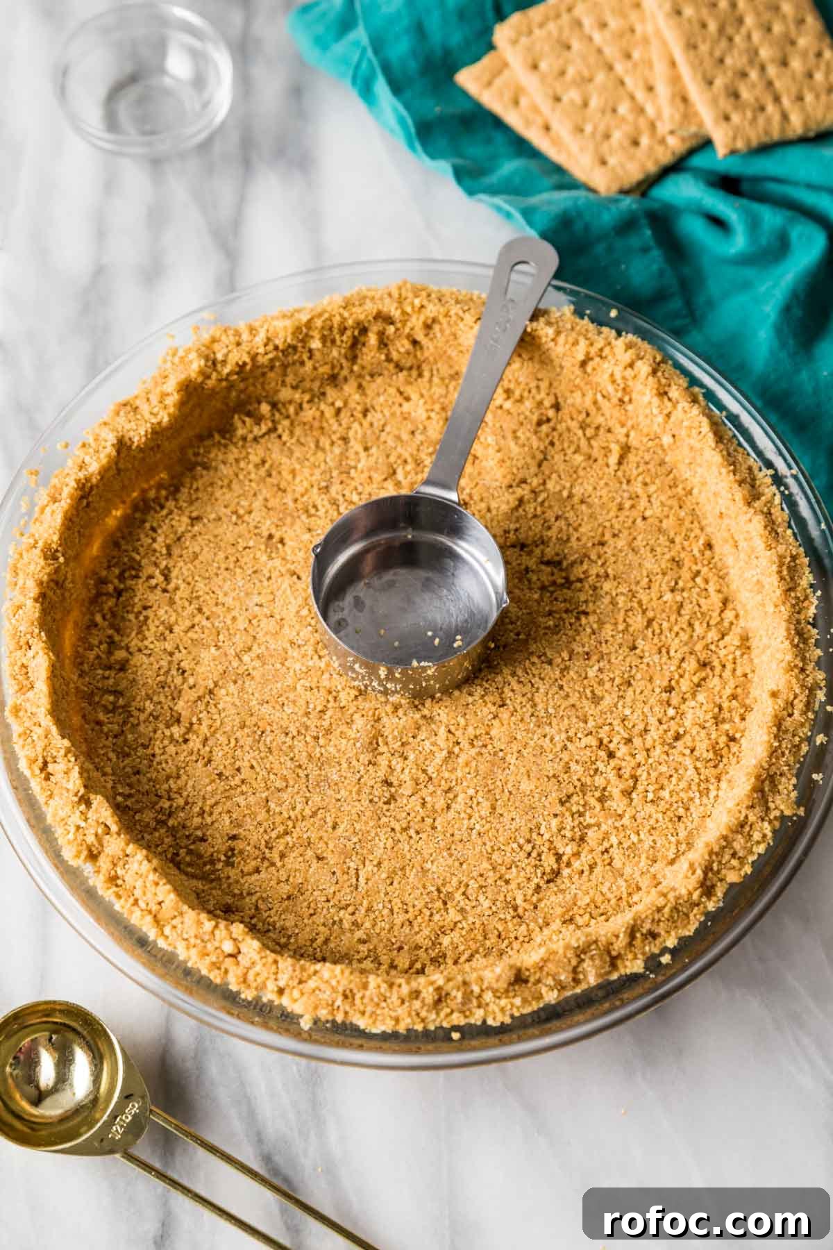 Graham Cracker Crust Recipe: Simple Steps for Perfect Pie Crust 10 Metal measuring cup sitting inside a prepared graham cracker crust.