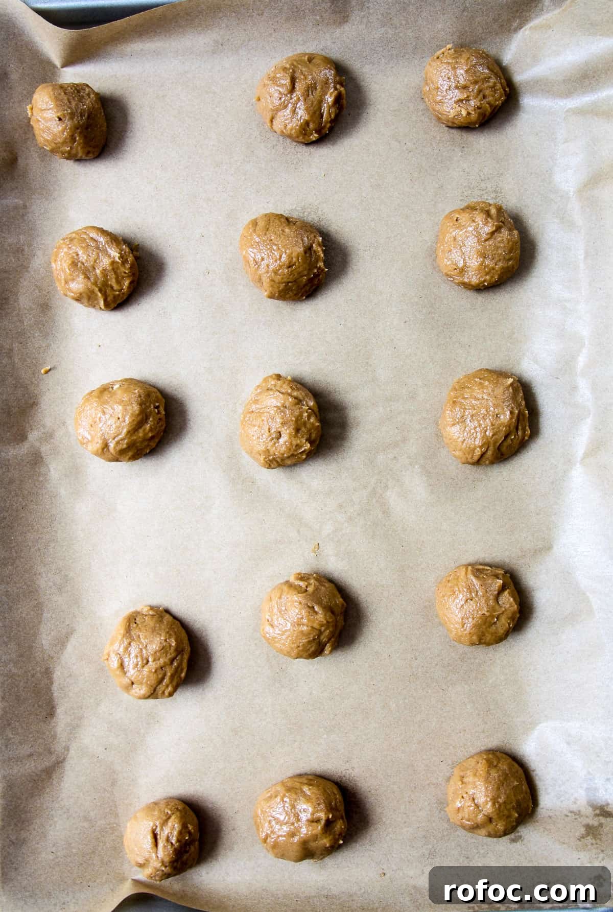 Cookie dough balls on a parchment lined baking sheet.