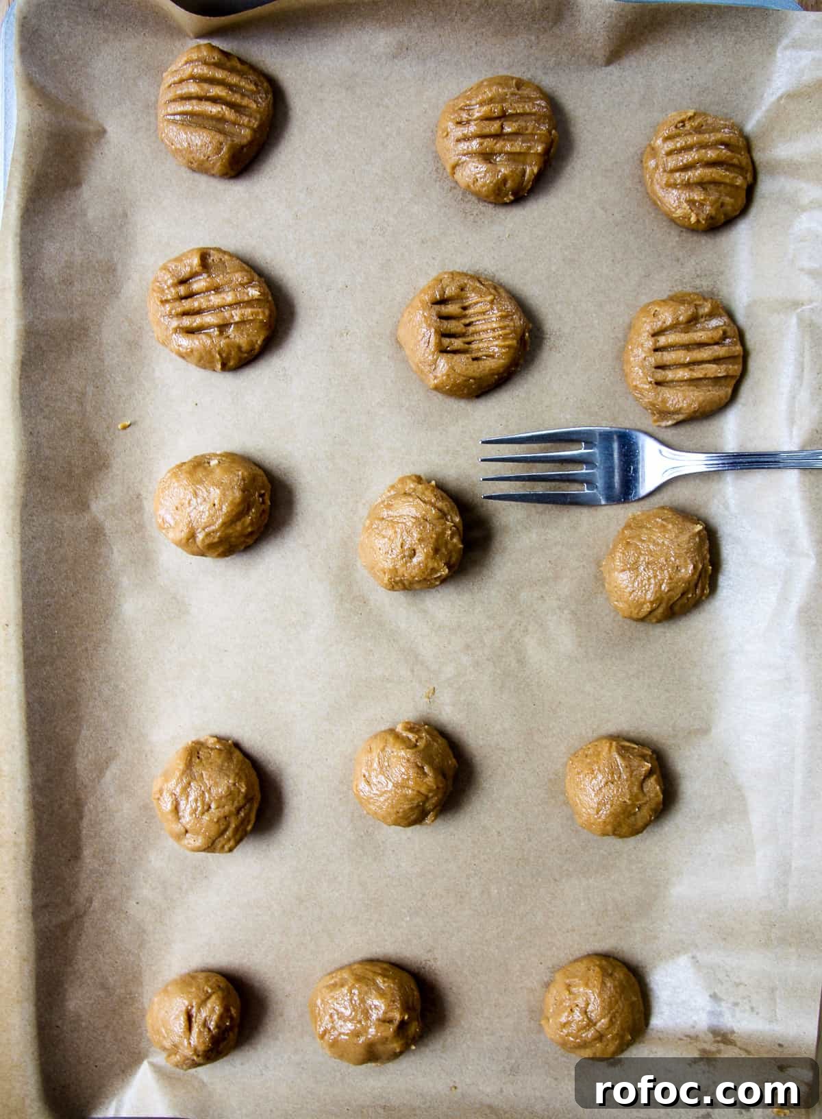 A fork being used to flatten the cookie dough balls.