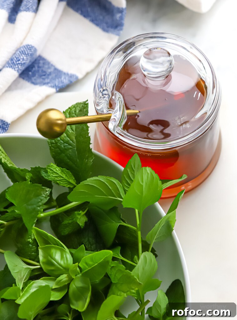 Refreshing Watermelon, Cucumber and Basil Salad 7 a while bowl filled with sweet basil, lemon basil and mint, and a jar of honey.