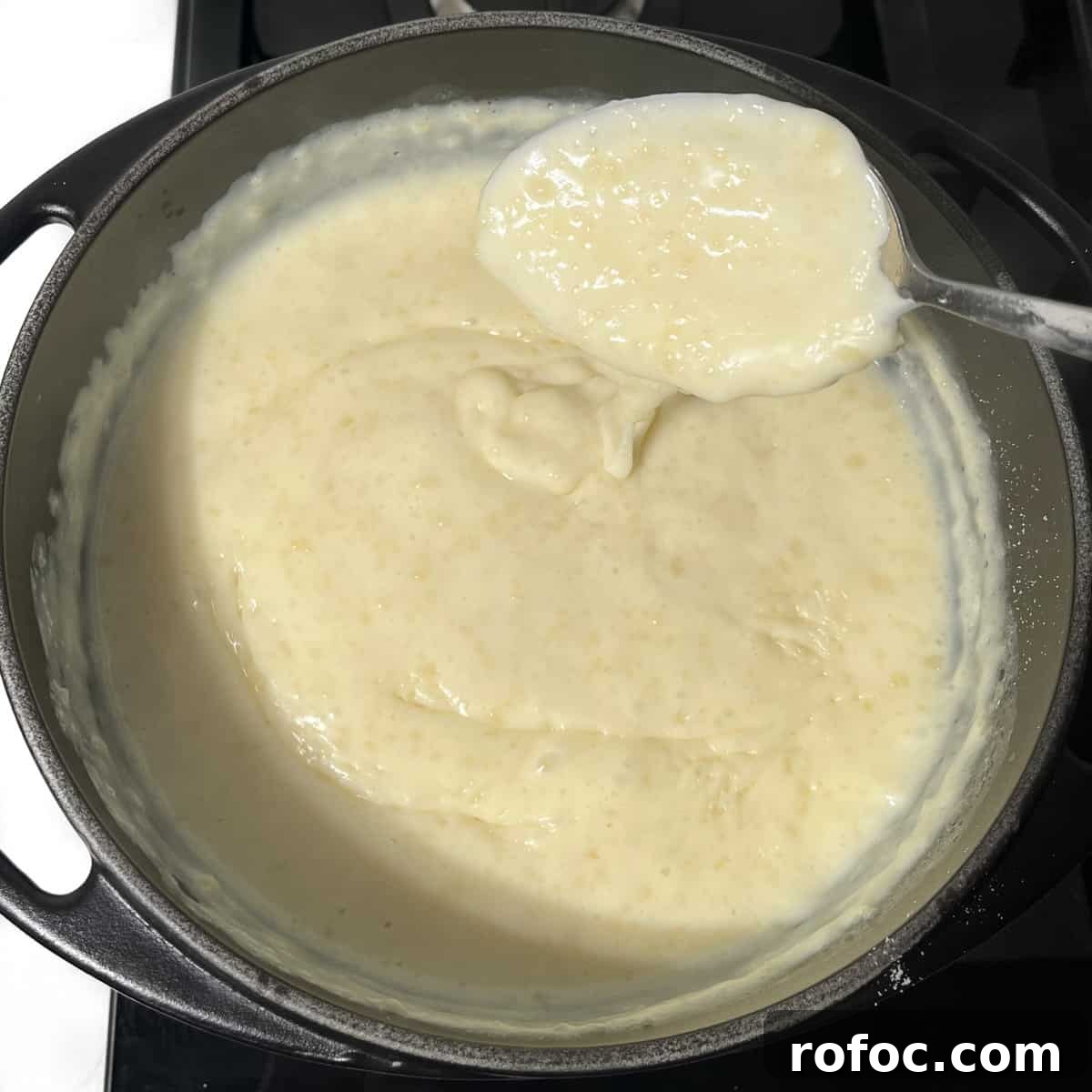 A large spoonful of melkkos over a black saucepan.