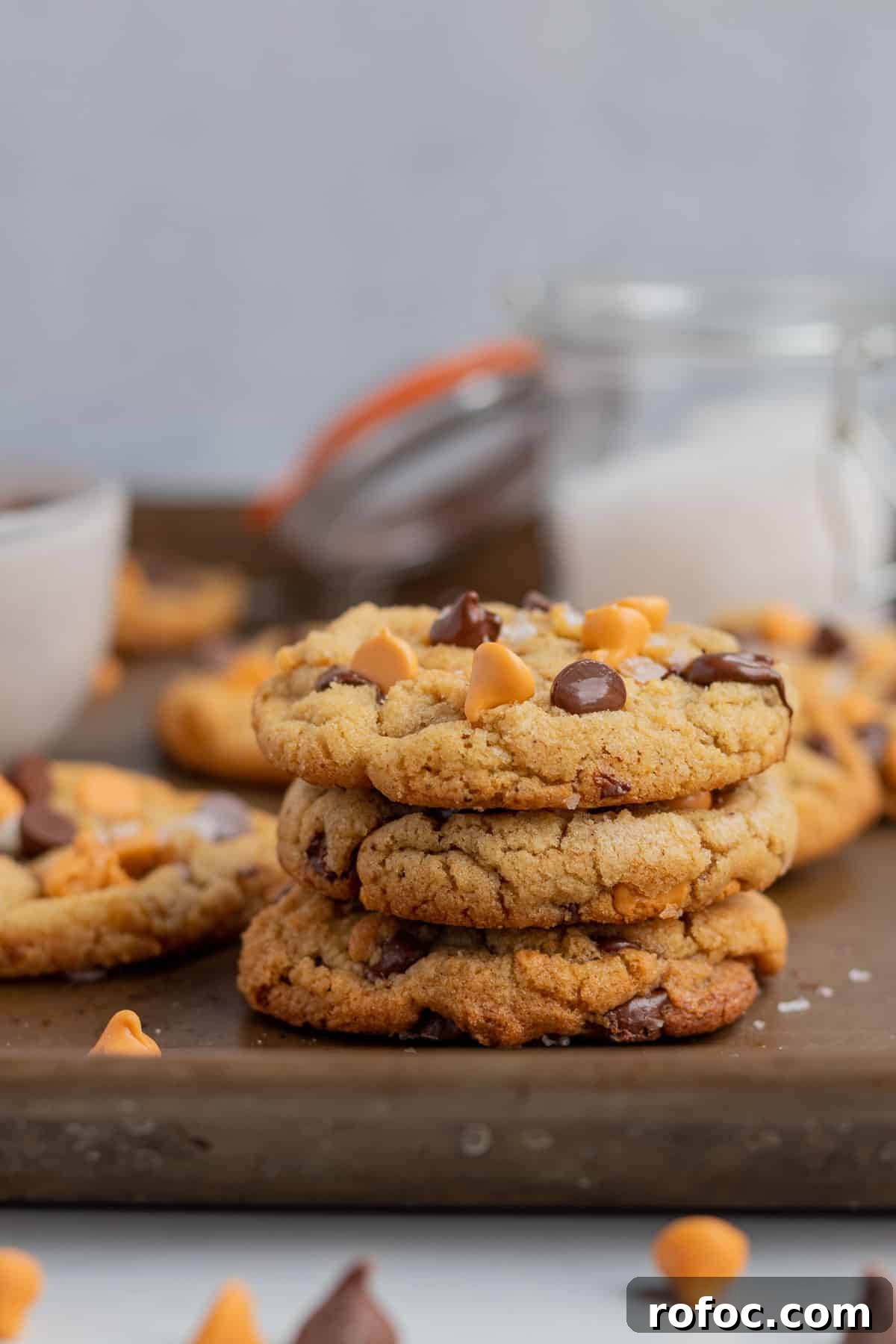 a stack of 3 chocolate chip butterscotch cookies with a glass jar of salt in the background